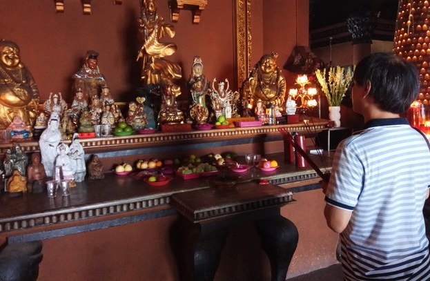 Juliman, pengunjung klenteng, sedang menyembah depan patung Dewi Kwan Im di Klenteng Sanggar Agung, Surabaya. (Foto: Amir Tejo/ngopibareng.id) 