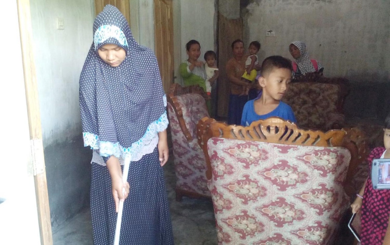Khosik sedang menyapu rumahnya di Desa Dungun, Kecamatan Tongas, Kabupaten Probolinggo. (Foto: Ikhsan/ngopibareng.id)