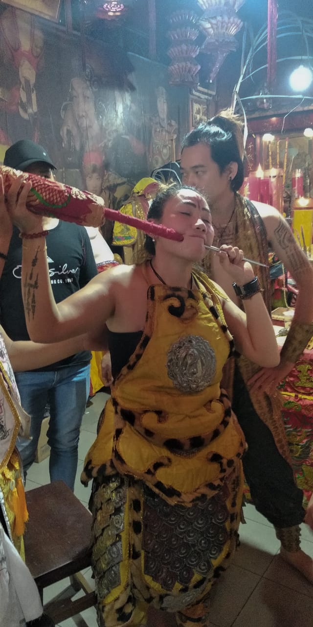 Tatung perempuan sedang memperlihatkan atraksi menusuk pipinya hingga nembus. Luar biasa, ini hanya ada di Singkawang. Jangan ditiru sembarangan. (Foto:Istimewa for ngopibareng.id)