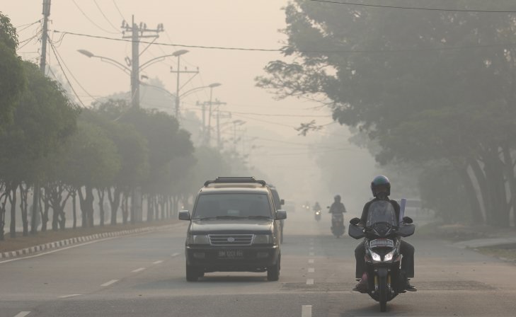 Arsip Foto-Warga melintas di jalan yang berkabut asap pekat dari kebakaran hutan dan lahan (karhutla) di kota Dumai, Dumai. Riau, Sabtu 23 Februari 2019. Kabut asap pekat yang berasal dari karhutla menjadi ancaman besar bagi kesehatan warga Kota Dumai dan otoritas kesehatan setempat menemukan sebanyak 180 kasus per hari pada pasien yang terinfeksi saluran pernafasan atas (ISPA). (Foto: Antara/Aswaddy Hamid)