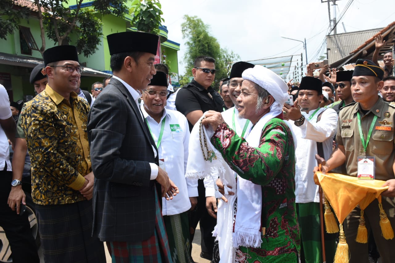 Presiden Joko Widodo disambut sorban oleh KH Munawir Abdurrohim, Pengasuh Pondok Pesantren Miftahul Huda Al-Azhar Citangkolo, Kota Banjar. (Foto: nu for ngopibareng.id)