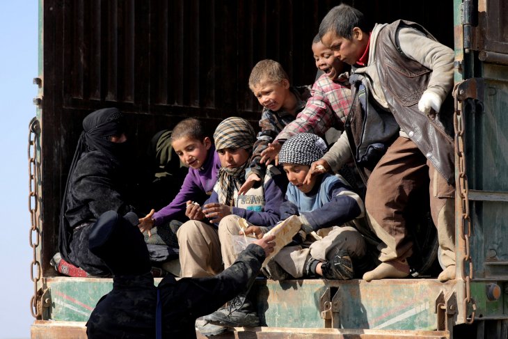 Seorang pejuang dari Pasukan Demokratik Suriah (SDF) memberikan roti kepada anak-anak di dekat desa Baghouz, Provinsi Deir al- Zor, Suriah. (Foto: Antara/Reuters)