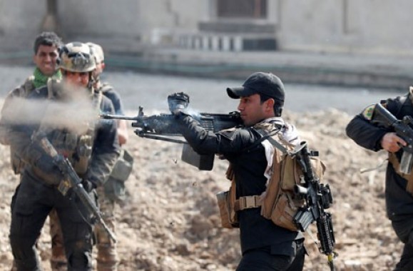 Seorang tentara pasukan khusus Irak menembakkan senjata sementara lainnya berlari menyeberang jalan saat bertempur di Mosul, Irak, Rabu, 1 Maret 2017. (Foto: reuters/antara)