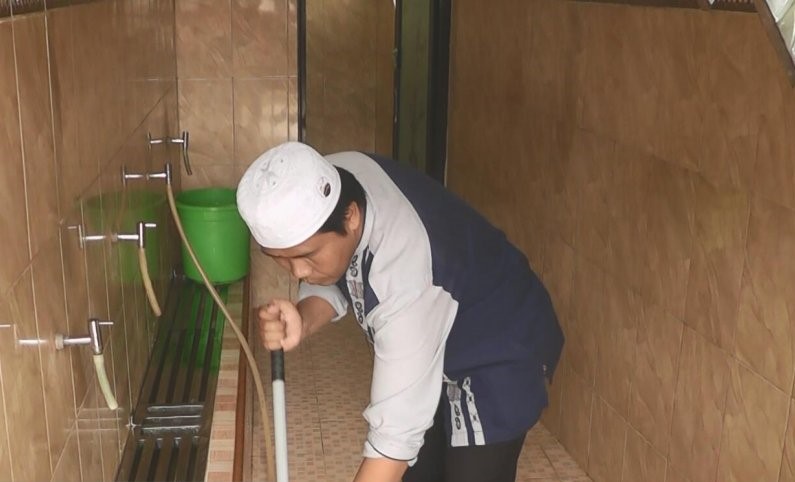 Ibrahim saat membersihkan tempat wudlu di Masjid Sami Al Huda, Palembang. (Foto: dolly/antara)