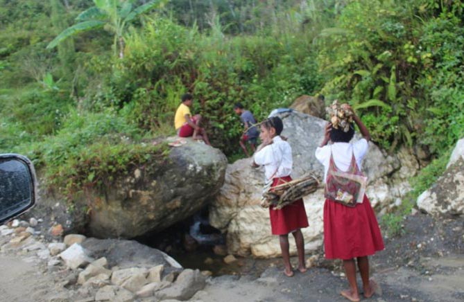 Dua orang siswa SD yang bersekolah di wilayah perbatasan antarkabupaten Yalimo dan Jayawijaya, saat menuju sekolah dengan membawa kayu bakar. (Foto: Antara/Marius Frisson Yewun)