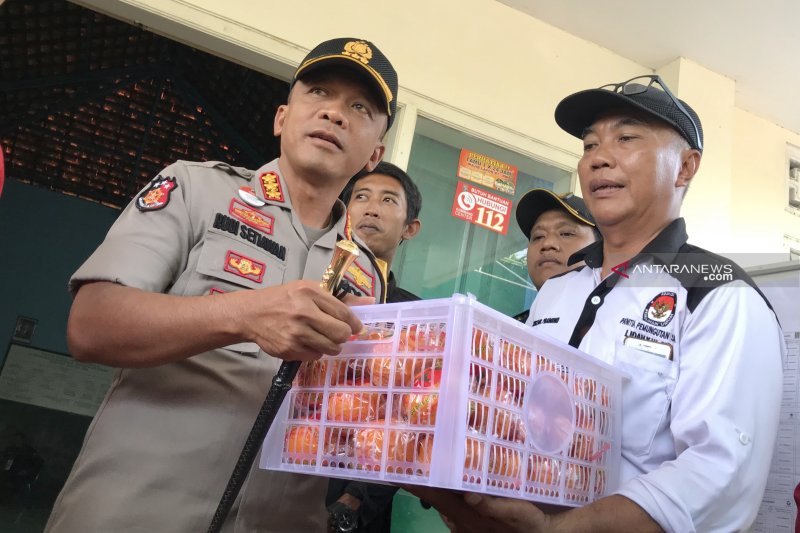 Kapolrestabes Surabaya Kombes Pol Rudi Setiawan (kiri) saat memberikan jeruk kepada petugas penyelenggara Pemilu yang diwakili Ketua PPS Kelurahan Lidah Kulon Sugeng Pramono di TPS 11, Sabtu 27 April 2019. (Foto: Fiqih Arfani)