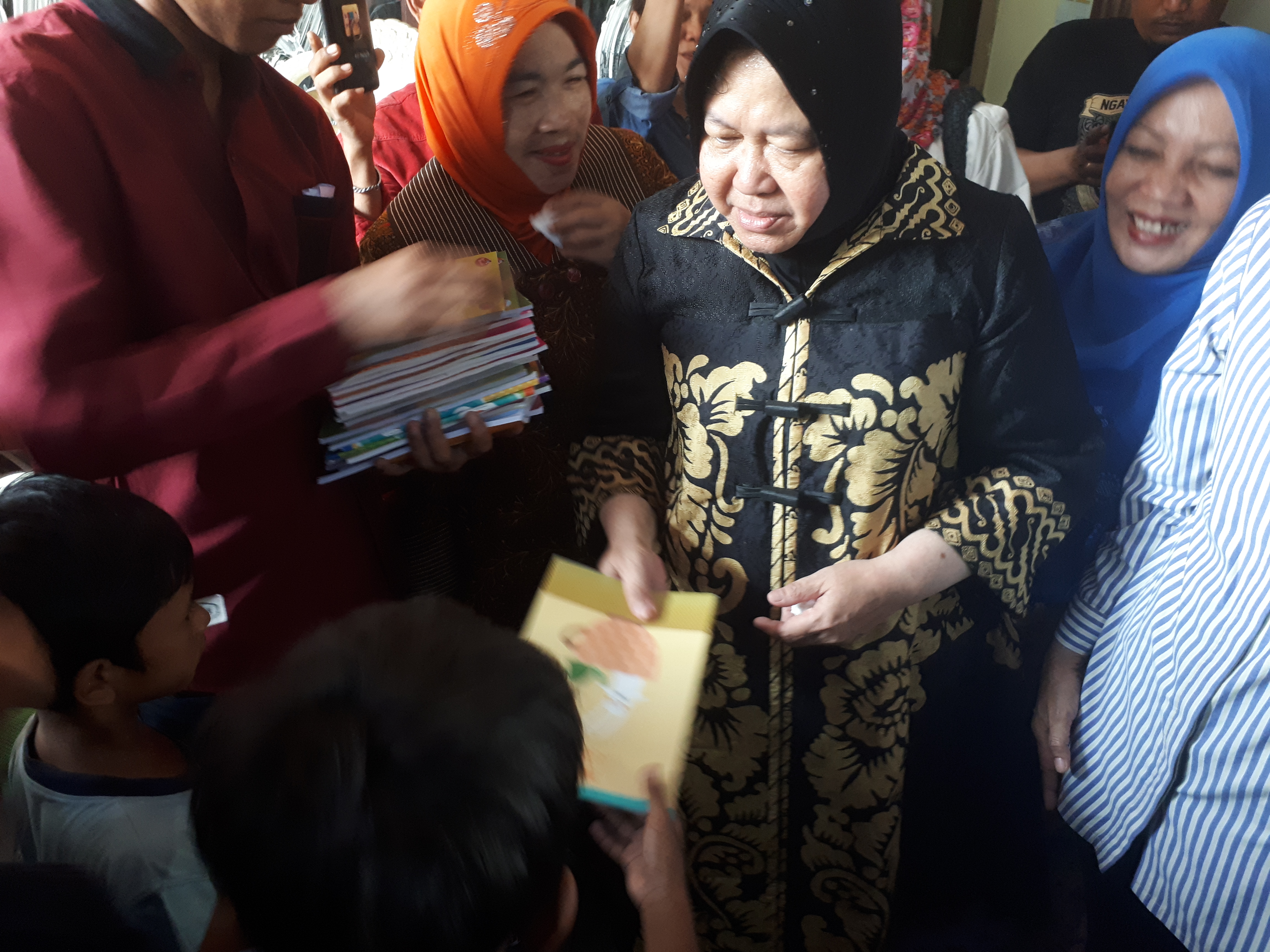 Risma membagikan buku setelah takziyah ke rumah almarhum anggota KPPS yang meninggal dunia. (Foto: Alief/ngopibareng.id)