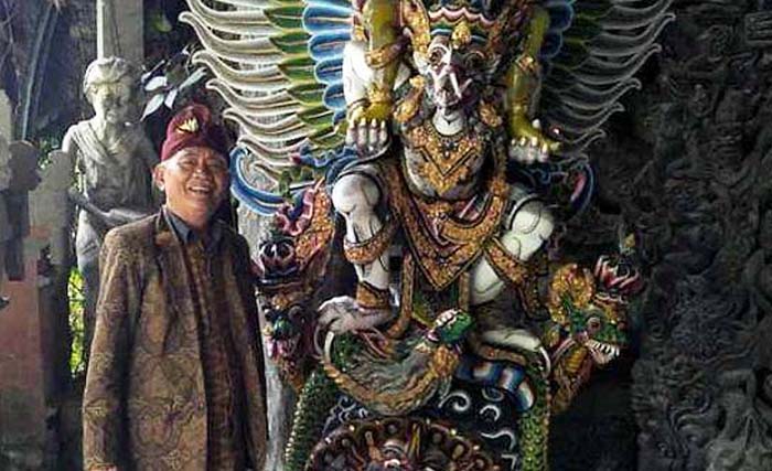 Made Ada, 71 tahun, di sisi patung garuda karyanya. (Foto:Balipost)