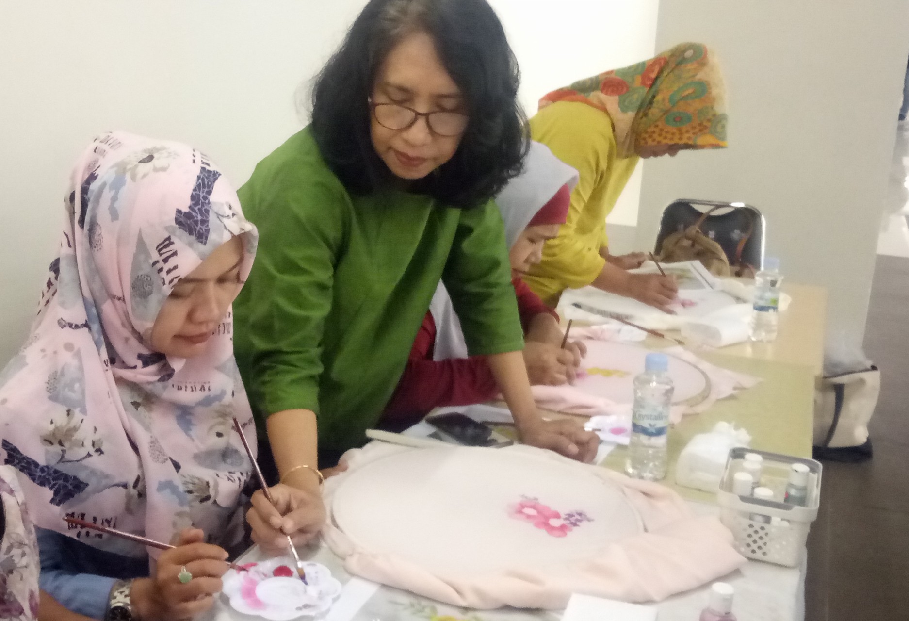 Tjiplies Pudji Lestari (tengah)  saat mengarahkan satu per satu ibu-ibu yang sedang melukis kerudung di lantai 2 Royal Plaza, Sabtu, 11 Mei 2019. (Foto: Pita/ngopibareng.id)