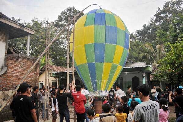 Warga menerbangkan balon udara di Desa Bandung, Kecamatan Diwek, Kabupaten Jombang, Jawa Timur, Minggu (2/7). Tradisi menerbangkan balon udara raksasa bersamaan di tiap musholah ini untuk merayakan Lebaran Ketupat atau biasa disebut Kupatan. (Foto: Antara/Syaiful Arif)