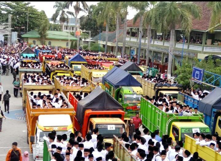  Ribuan peserta tes masuk Pondok Moderen Gontor diangkut dengan puluhan truk. Mereka harus menjalani tes lisan dengan tes tulis yang lokasinya berbeda. Untuk tes lisan dilakukan di Pondok Gontor II  sedang tes tulis di Pondok Gontor I. Untuk berpindah ke Pondok II ke I peserta tes diangkut menggunakan truk terbuka karena jaraknya sekitar 6,2 km. (Foto: Novi to ngopibareng.id)