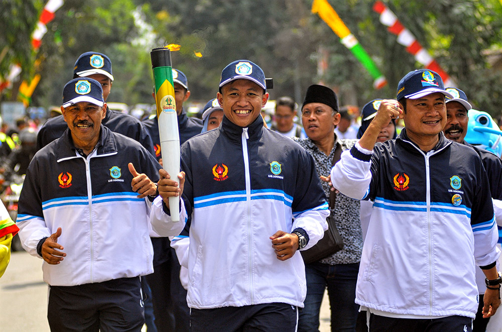 Sekda Lamongan, Yuhronur Efendi (kanan) berlari bersama pembawa api porprov, untuk diberikan kepada Pemkab Gresik, yang diwakili oleh Sekda Gresik, Andhy Hendro. Rabu, 3 Juli 2019. (Foto: Erfan/ngopibareng.id)