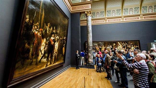 Sebelum mulai direstorasi, para pengunjung memperhatikan lukisan karya Rembrandt, The Night Watch atau Penjaga Malam, di Rijksmuseum di Amsterdam. (Foto:CBC)