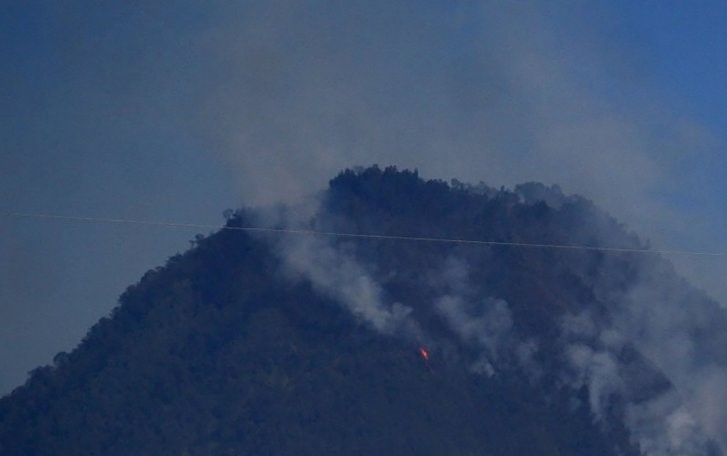 Asap terlihat mengepul dari puncak dan lereng Gunung Panderman, Kota Batu, Jawa Timur, Senin 22 Juli 2019. (Foto: Antara)