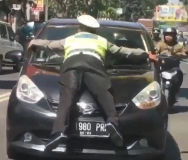 Tangkapan layar polisi naik ke kap mobil