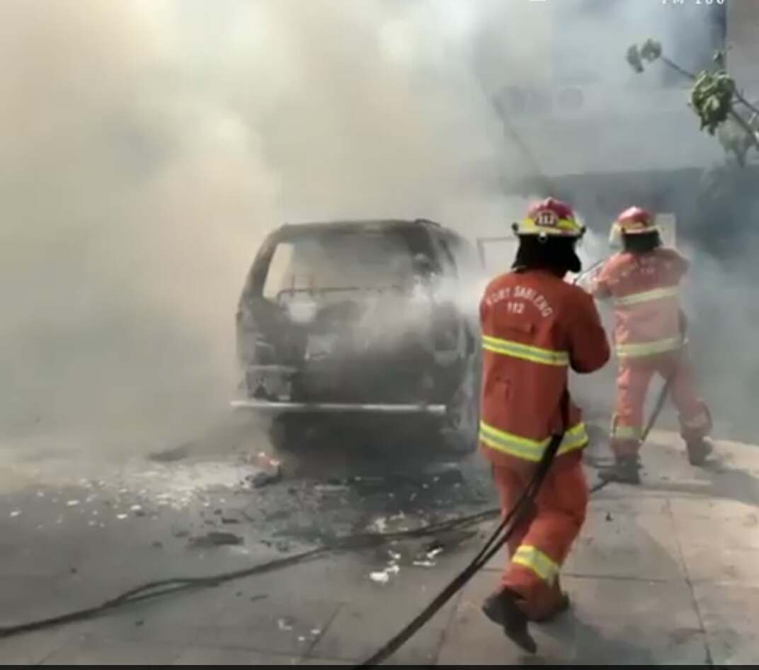 Petugas sedang memadamkan mobil yang terbakar. 