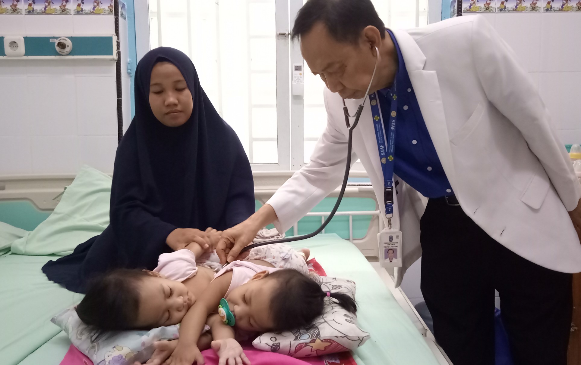 Ketua Tim Pusat Pelayanan Kembar Siam Terpadu, dr. Agus Harianto,SpA (K) saat memeriksa keadaan bayi kembar siam asal kendari (Nb: minta tolong foto di blur wajah bayinyya)  (Foto: Pita/ngopibareng.id)