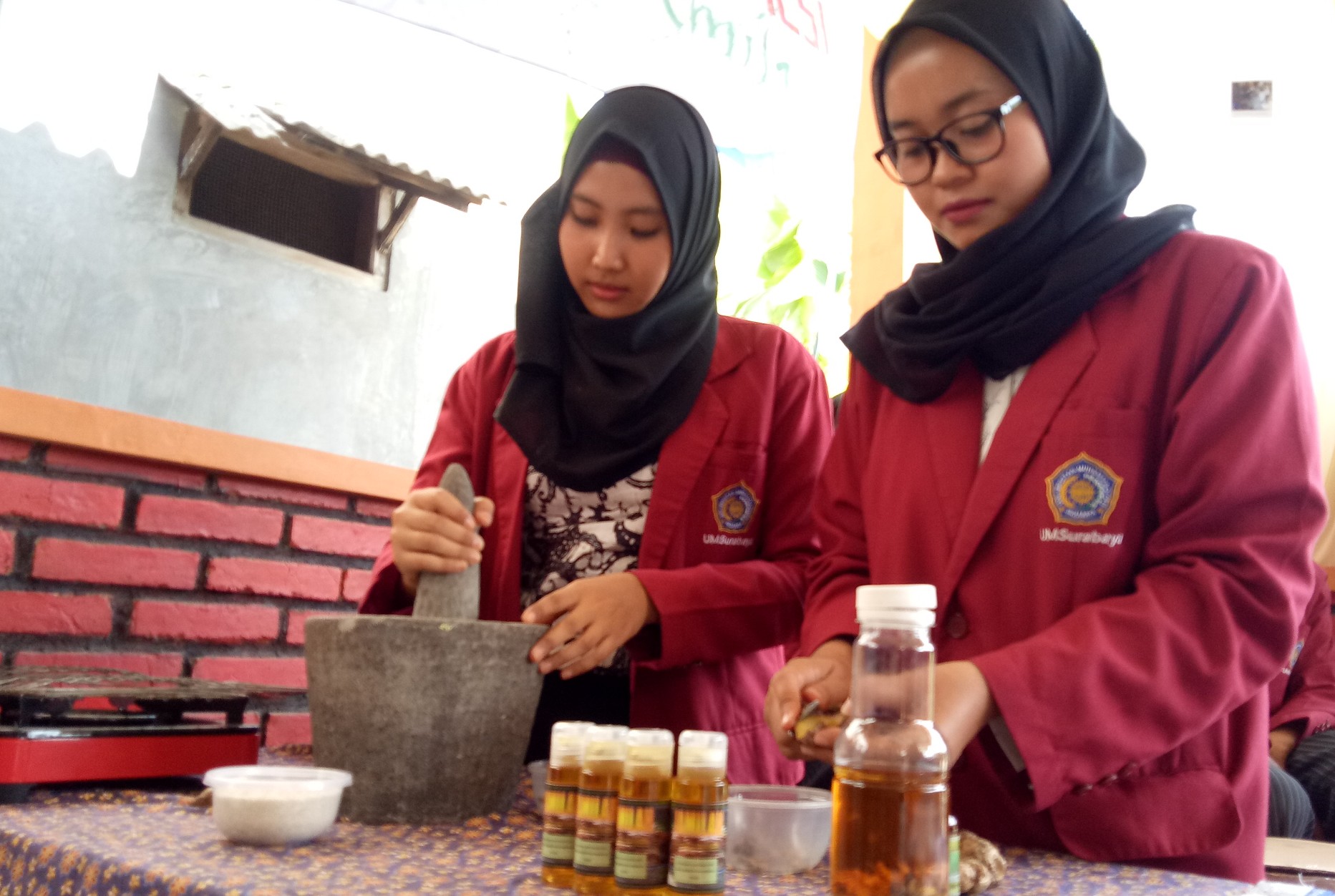 Mahasiswa UMS sedang menunjukan proses pembuatan minyak Jamila di Balai Kelurahan Medokan Semampir, Surabaya. (Foto: Pita/ngopibareng.id)