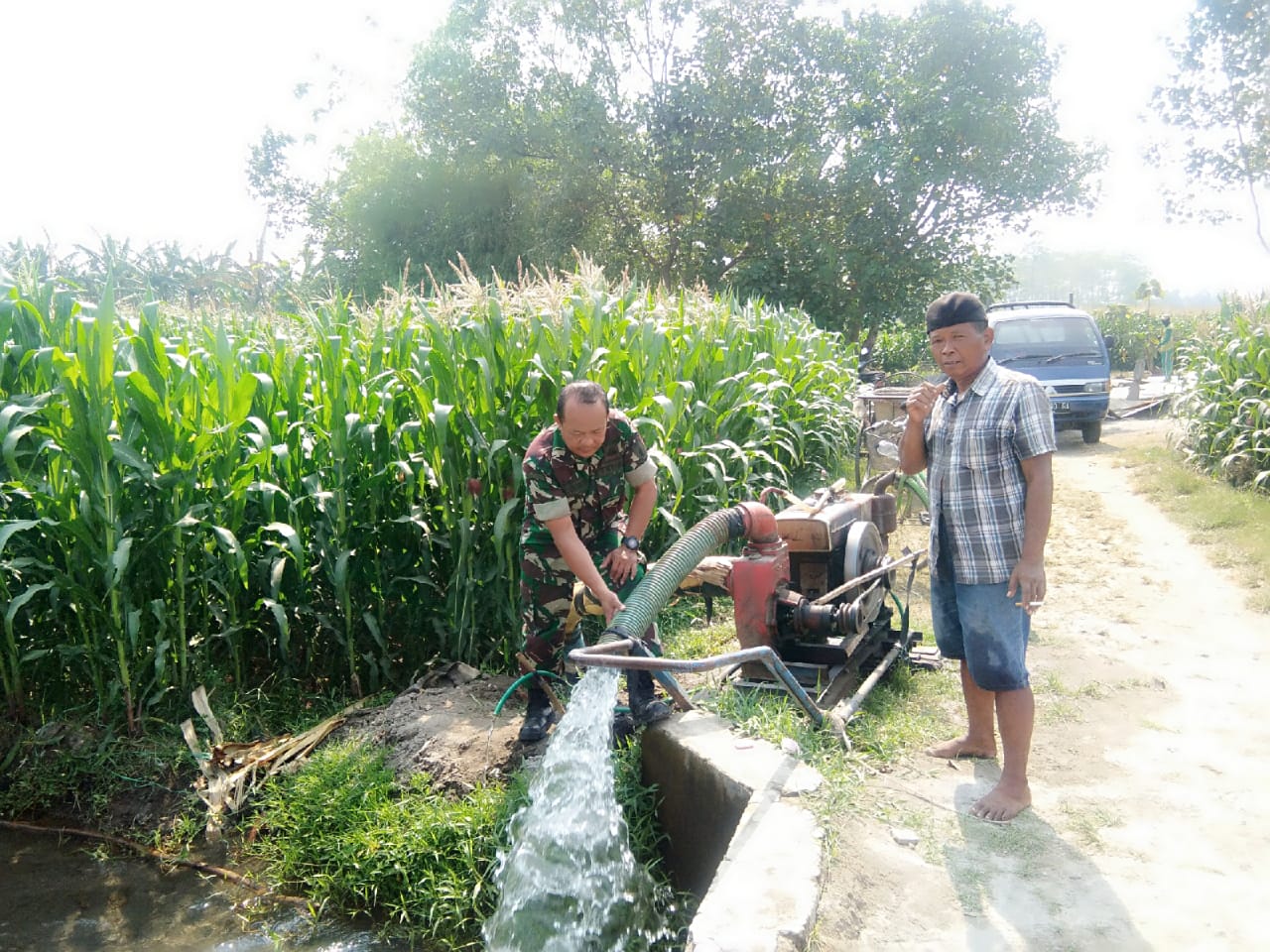 Serda Akmad Subandi saat memdampingi petani mengairi lahan tanaman jagung