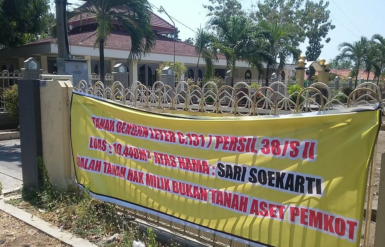 SPANDUK bertuliskan klaim warga atas tanahnya dengan latar belakang Masjid Al Hidayah. (Foto: Ikhsan/ngopibareng.id)