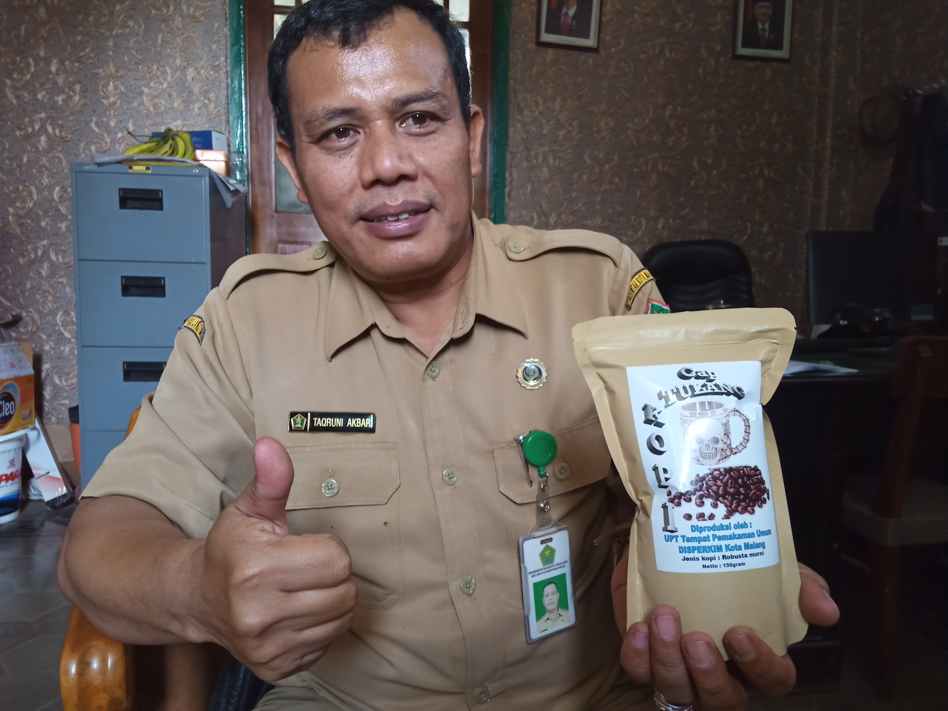 Kepala Unit Pelaksana Teknis (UPT) Tempat Pemakaman Umum (TPU) Dinas Perumahan dan Pemukiman, Kota Malang, Taqruni Akbar, saat memamerkan produk Kopi Tulang di kantornya (Foto: Theo/ngopibareng.id)