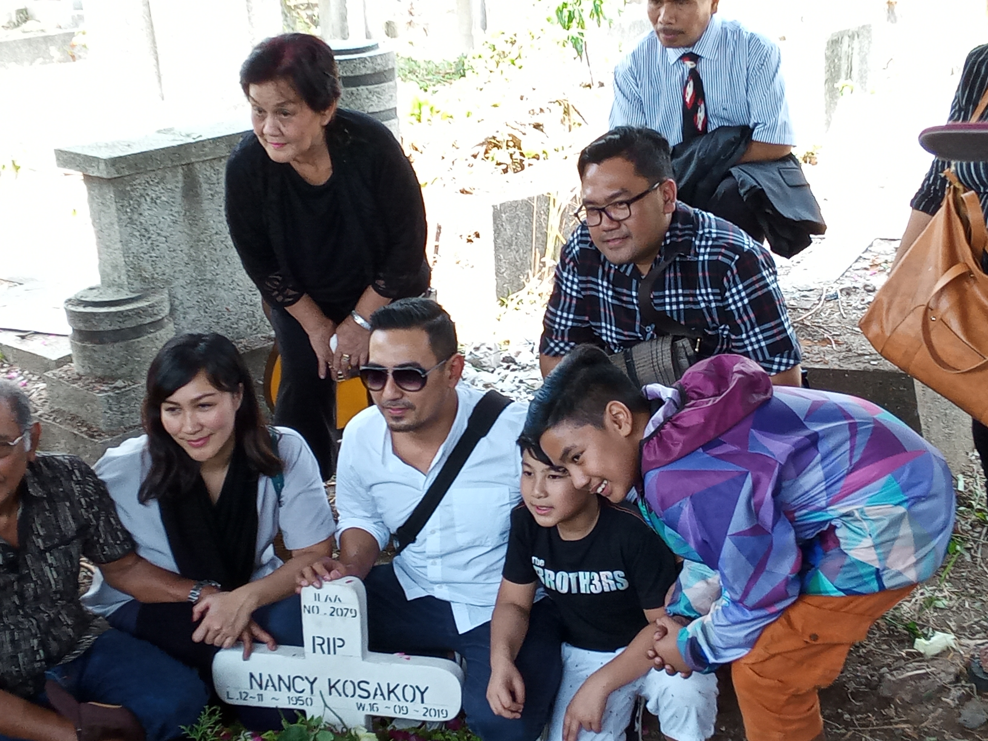 Rio Febrian beserta keluarga berfoto bersama di pusara ibunda tercinta. (Foto: Theo/ngopibareng.id)