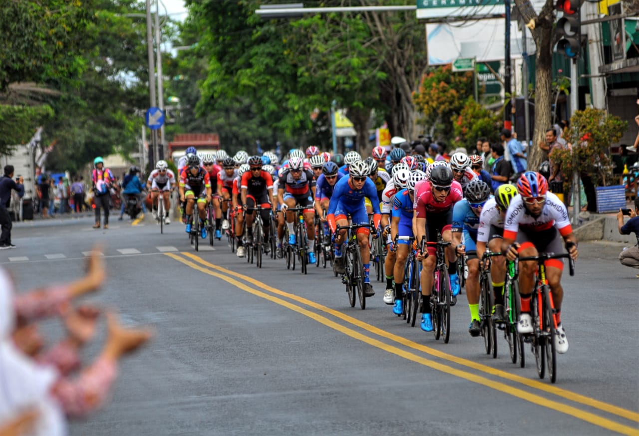 Pembalap saat melintas di Kecamatan Genteng, Kabupaten Banyuwangi. Etape pertama International Tour de Banyuwangi Ijen (ITdBI) 2019 menjadi milik pembalap asal Mongolia, Maral-Erdene Batmunkh dari Terengganu Inc. TSG Cycling Team (Malaysia). Batmunkh melahap rute sejauh 133,2 kilometer dengan catatan waktu 3 jam, 3 menit dan 36 detik.  disusul oleh Robbie Hucker dari Ukyo Team di posisi kedua dan  Jesse Ewart dari Sapura Cycling Team di posisi ke tiga. (Foto: Japrak/ngopibareng.id)