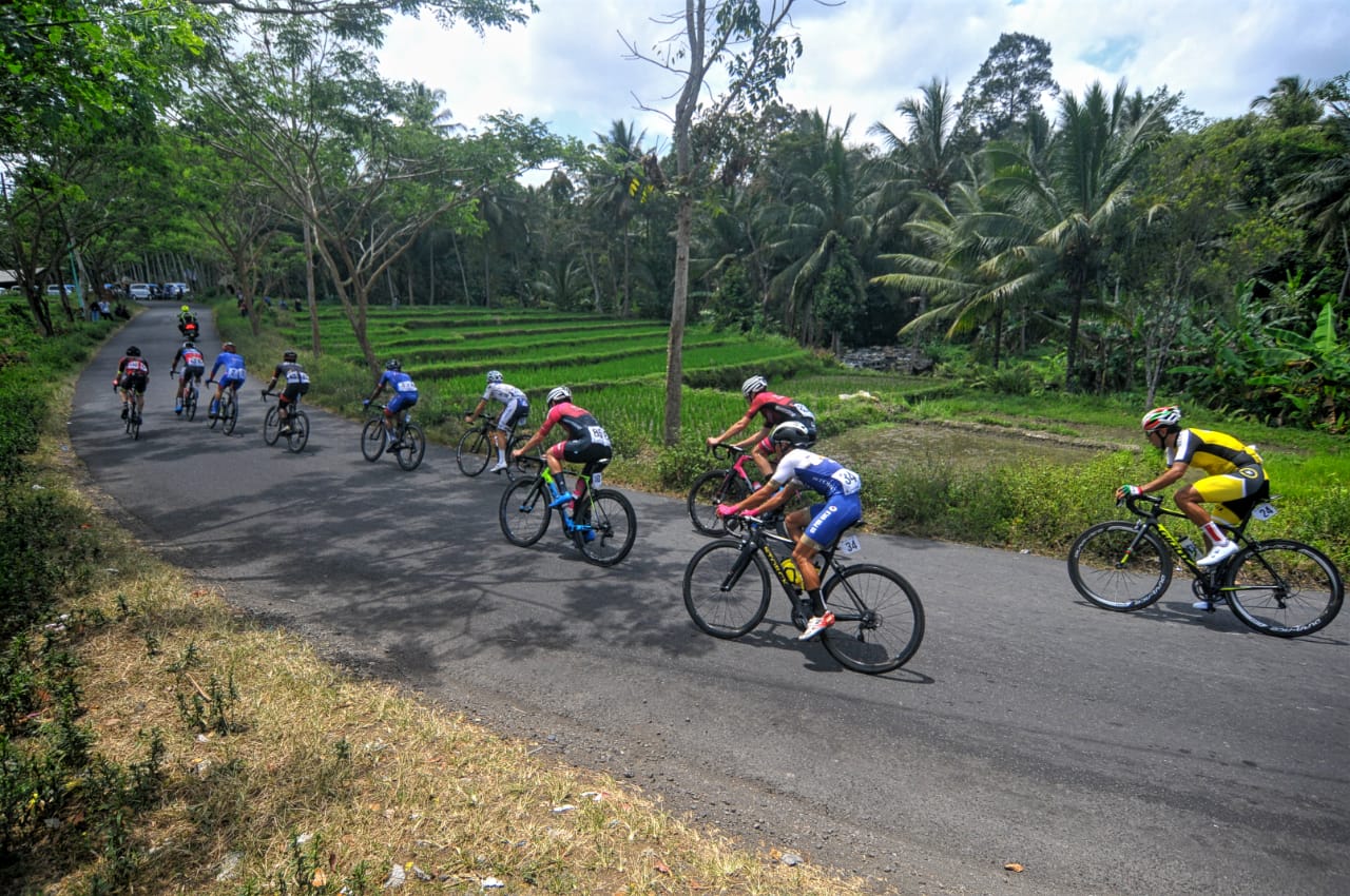 Pebalap saat melintas di area persawahan Kecamatan Songgon, Kabupaten Banyuwangi. Etape pertama International Tour de Banyuwangi Ijen (ITdBI) 2019 menjadi milik pembalap asal Mongolia, Maral-Erdene Batmunkh dari Terengganu Inc. TSG Cycling Team (Malaysia). Batmunkh melahap rute sejauh 133,2 kilometer dengan catatan waktu 3 jam, 3 menit dan 36 detik.  disusul oleh Robbie Hucker dari Ukyo Team di posisi kedua dan  Jesse Ewart dari Sapura Cycling Team di posisi ke tiga. (Foto: Japrak/ngopibareng.id)