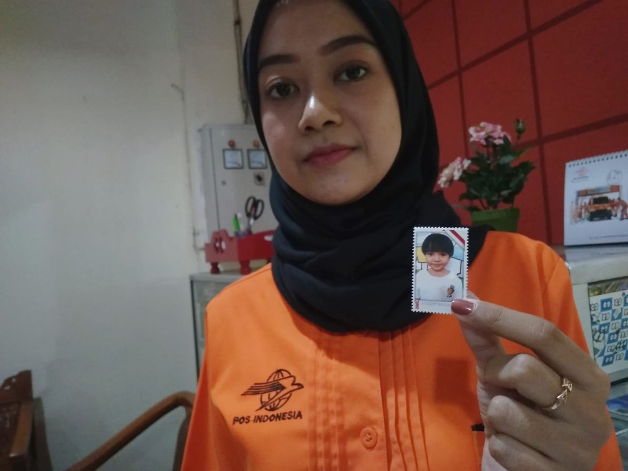 Humas sekaligus Admin Penjualan Kantor Pos Malang, Icha Puspita, memamerkan prangko dengan wajah sendiri yang bisa dibuat di Kantor Pos Malang. (Foto: Theo/ngopibareng.id)