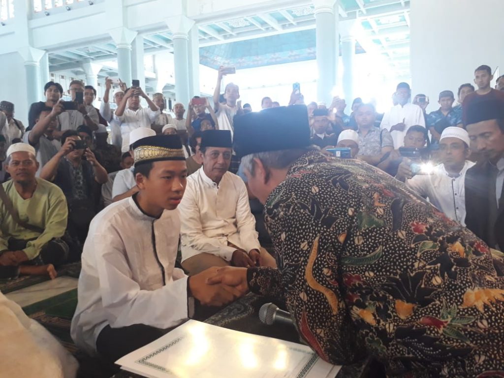 KH Marzuki Mustamar ketika mengikrarkan seorang di antara yang masuk Islam. (Foto: ist/ngopibareng.id)