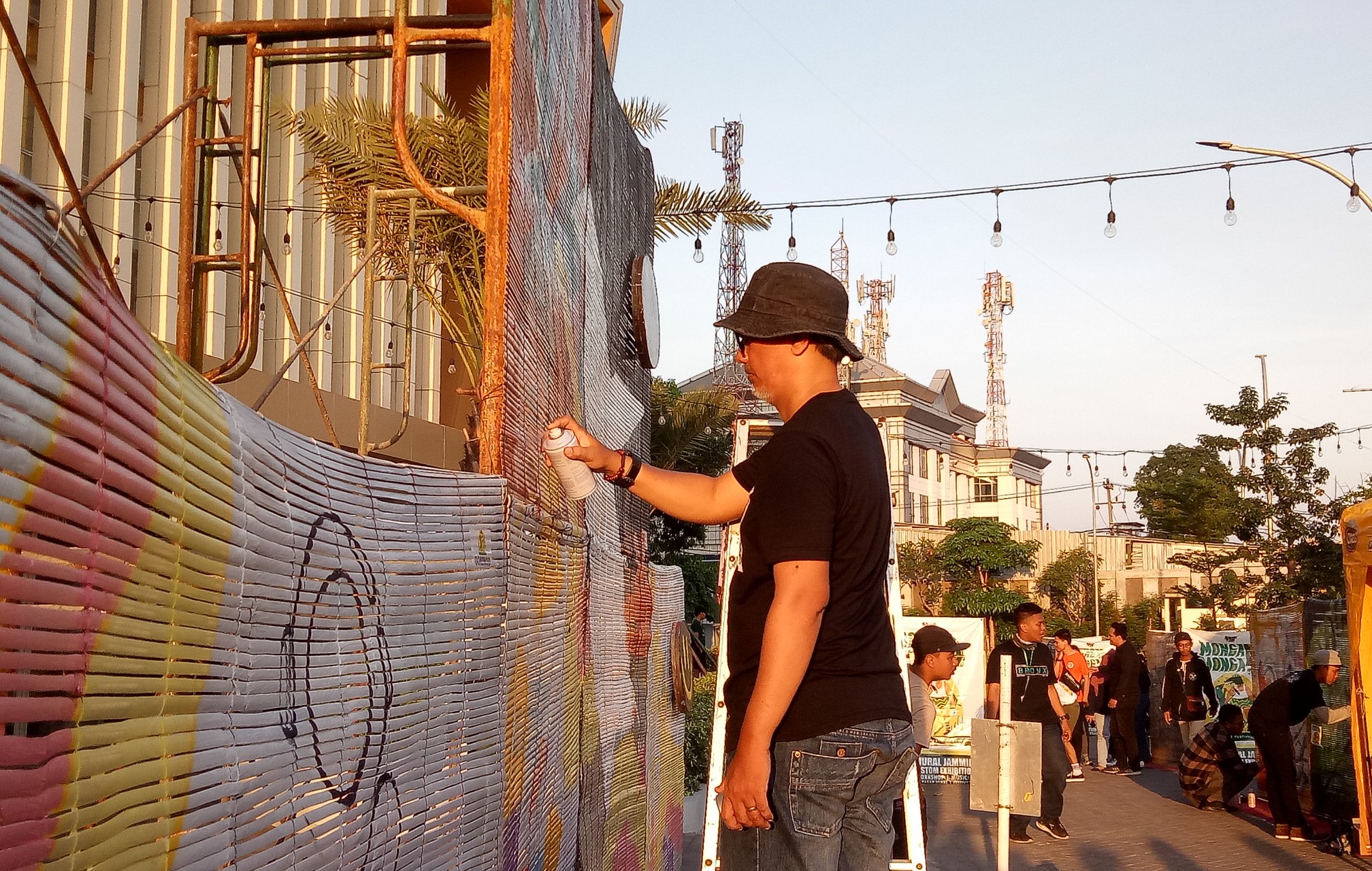 Uncle Joy seniman mural dari Bali saat menyelesaikan gambar muralnya di media bambu dalam 'Bamboo Mural Festival 2019' (Foto: Pita/ngopibareng.id)