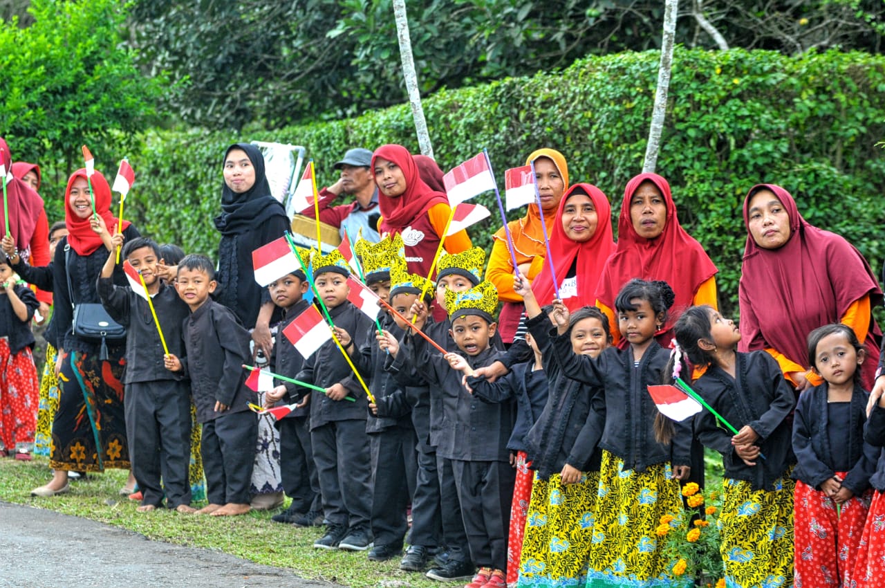 Dengan memakai pakaian adat suku Osing dan membawa bendera Merah Putih, anak-anak ini siap menyambut pembalap yang akan melintas di area pemukiman perkebunan Kali Bendo, Kecamatan Licin, Kabupaten Banyuwangi