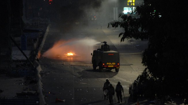 Polisi dengan mobil water canon berusaha memadamkan api yang dibakar pengunjuk rasa saat terjadi bentrokan di Jembatan Layang, Makassar, Sulawesi Selatan, Jumat 27 September 2019. [Foto: Antara/Abriawan Abhe]