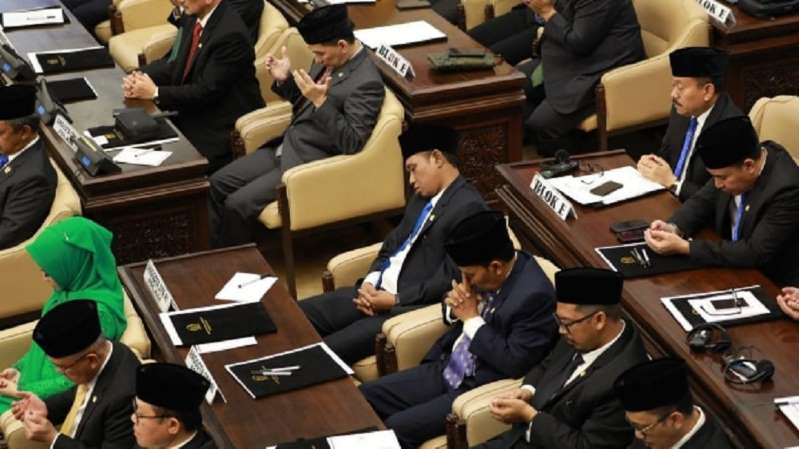 Anggota DPR Fraksi NasDem Lora Achmad Fadil Muzakki Syah (Lora Fadil) tertidur saat anggota DPR lainnya tengah berdoa di Gedung Nusantara DPR Senayan, Jakarta, Selasa 1 Oktober 2019.