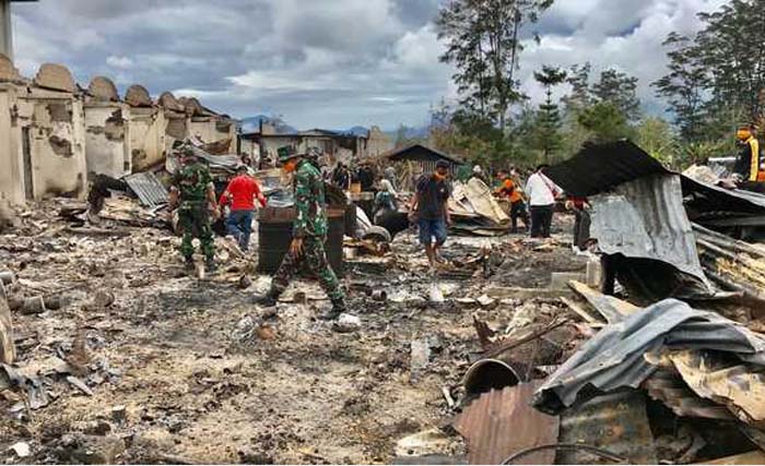 Anggota TNI dan masyarakat membersihkan puing-puing di Pasar Pasar Woma, Wamena, Papua. (Foto:BeritaSatu)