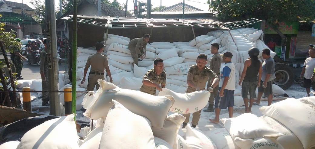 Sinergi TNI-Polri dan Satpol PP evakuasi tepung berserakan di jalan, akibat truk gandeng terguling. (Foto: Fendi/ngopibareng.id)