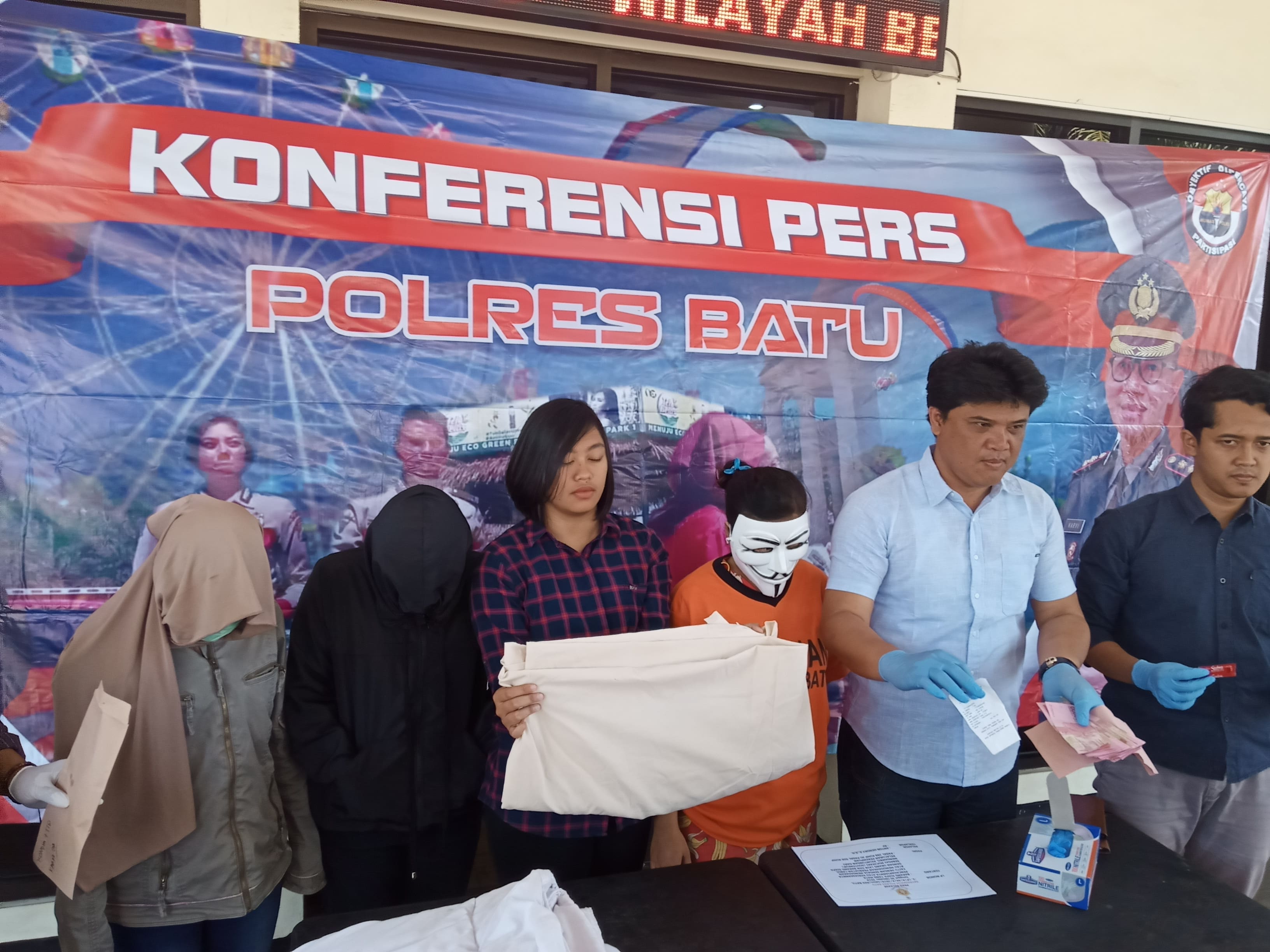 Tersangka muncikari R saat rilis pers di halaman Mapolresta Batu (Theo/ngopibareng.id)