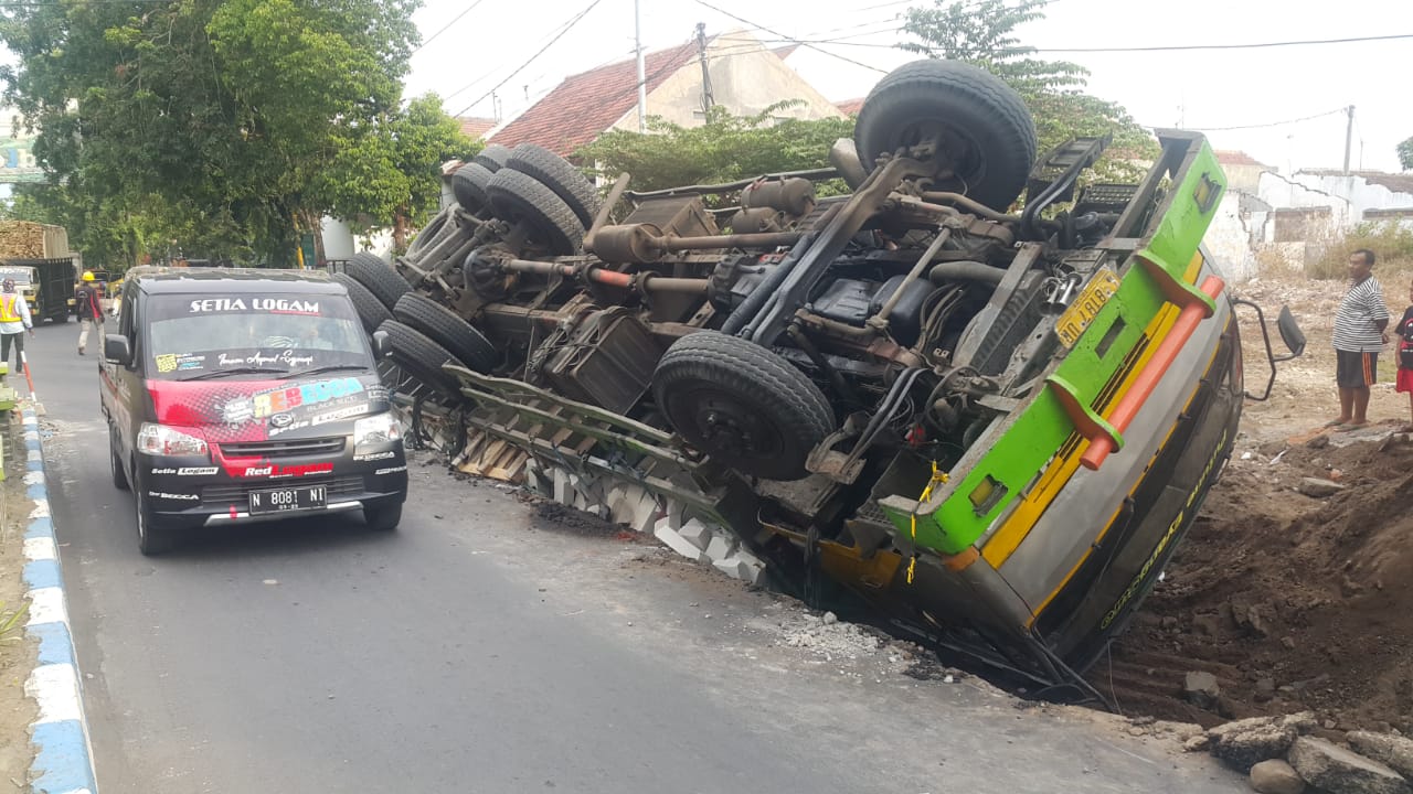 TRUK trailer bermuatan bata ringan terperosok galian proyek dan terguling di Jalan Panglima Sudirman, Kota Probolinggo. (foto: Ikhsan/ngopibareng.id)