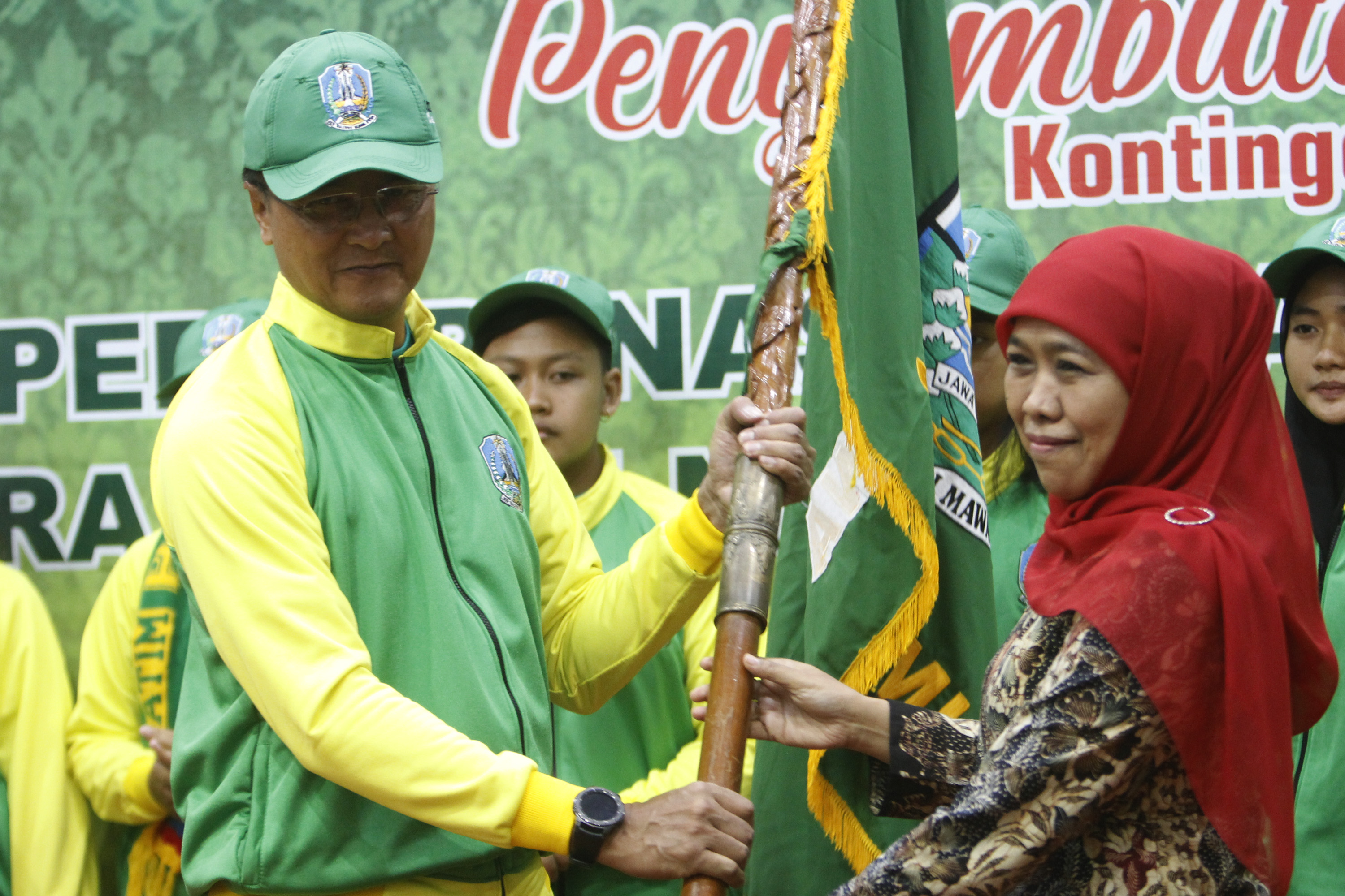 Gubernur Jatim, Khofifah Indar Parawansa (kanan) menyerahkan bendera Jatim kepada Komandan Kontingen Popnas Jatim, Supratomo dalam pelepasan tim Popnas di Gedung Negara Grahadi, Surabaya, Jumat 15 November 2019. (Foto: Fariz/ngopibareng.id)