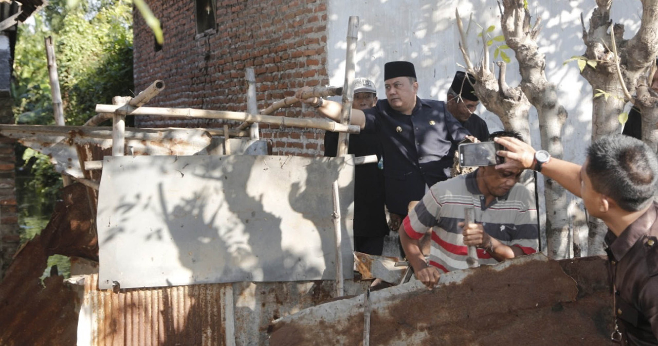 Wakil Wali Kota Probolinggo, HMS Subri (baju hitam dan berpeci) saat ikut membongkar ‘jamban helikopter’ di Kelurahan Pilang, Kecamatan Kademangan, beberapa waktu lalu. (Foto: Ikhsan/ngopibareng.id)