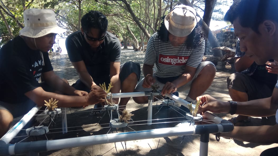 Wisatawan mempraktekkan langsung cara menanam terumbu karang di destinasi wisata Bangsring Under Water (foto : Hujaini/ngopibareng.id)