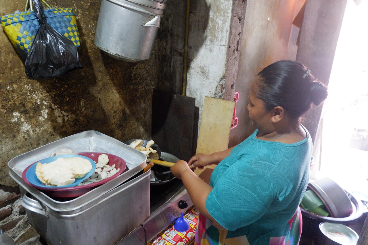 FATMAWATI, warga Mayangan, Kota Probolinggo sedang menggoreng kerupuk ikan di atas kompor yang tersambung ke jargas. (Foto: Ikhsan/ngopibareng.id)