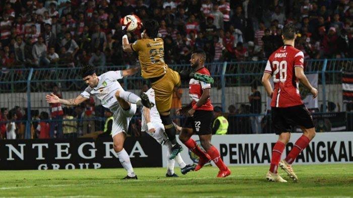 Kiper Madura United Muhammad Ridho mengamankan bola-bola atas dari serbuan pemain depan Persebaya. (Foto: tribunnews.com)