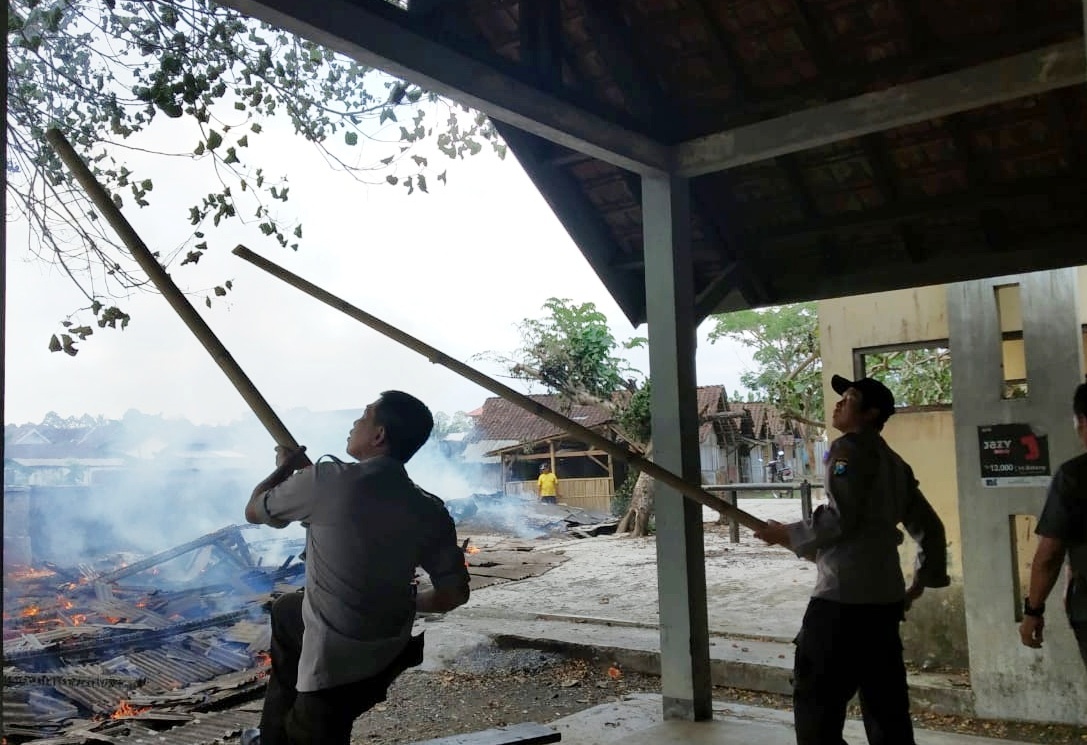 Petugas Polsek Glenmore mencoba memadamkan api dengan alat seadanya. (Foto: Hujaini/Ngopibareng.id)