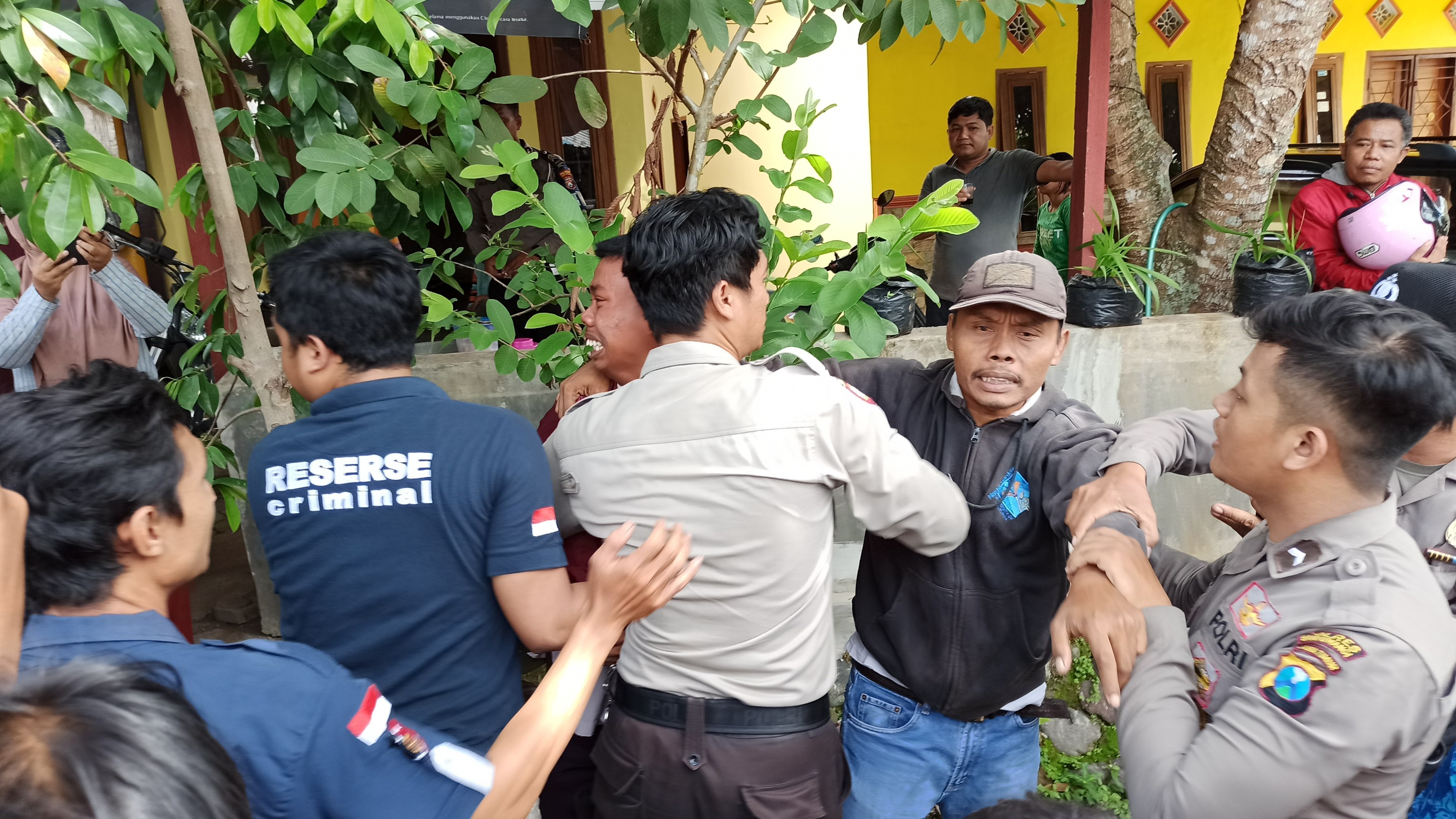 Petugas mencoba menenangkan keluarga korban yang hendak mendekati Hendrik Tibboel usai proses rekonstruksi. (Foto: Hujaini/ngopibareng.id)