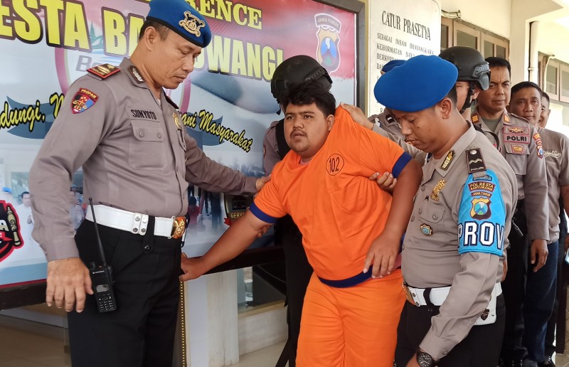 Tersangka pembunuh Rosidah dikawal anggota Polres Banyuwangi. (Foto: Hujaini/ngopibareng.id)