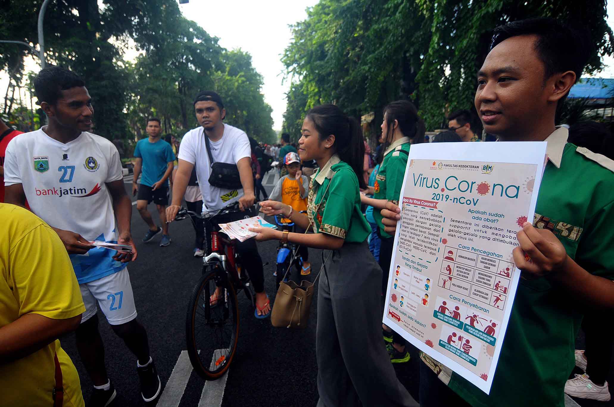 Mahasiswa Fakultas Kedokteran Ubaya membagikan leaflet yang berisi informasi mengenai virus corona di Taman Bunggkul. (Foto: Erfan Hazransyah/ngopibareng.id)