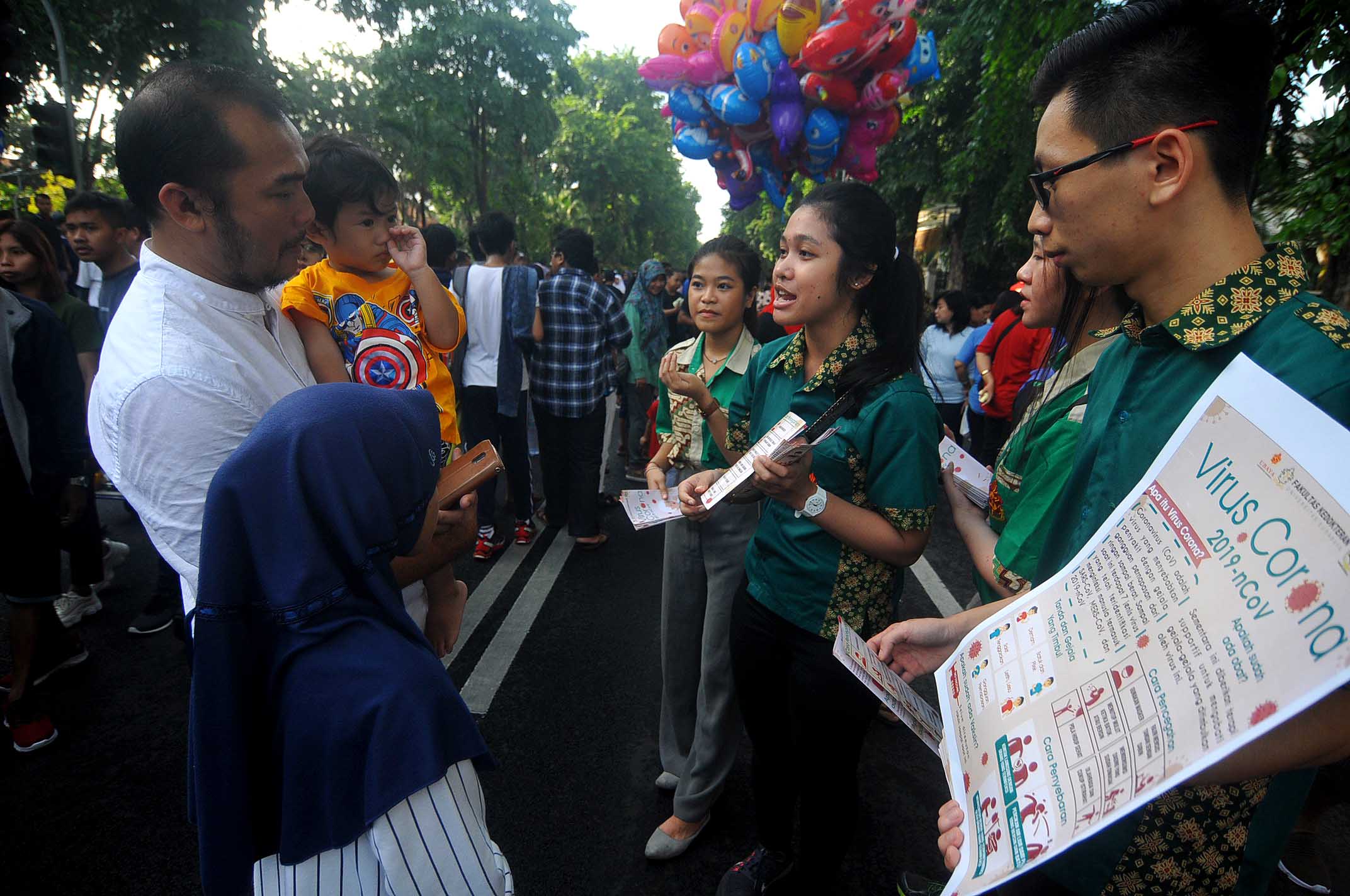 Mahasiswa Fakultas Kedokteran Ubaya menerangkan kepada warga mengenai gejala, cara penyebaran, dan pencegahan virus Corona.  (Foto: Erfan Hazransyah/ngopibareng.id)