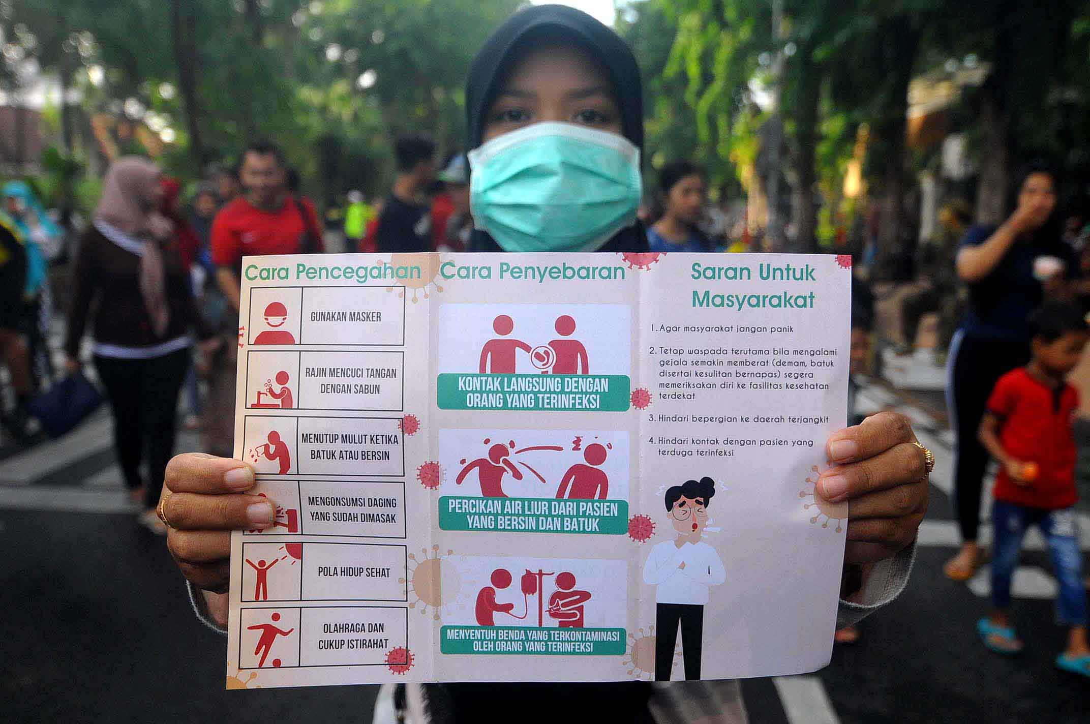 Seorang warga memerlihatkan leaflet yang berisi informasi mengenai virus corona (Foto: Erfan Hazransyah/ngopibareng.id)