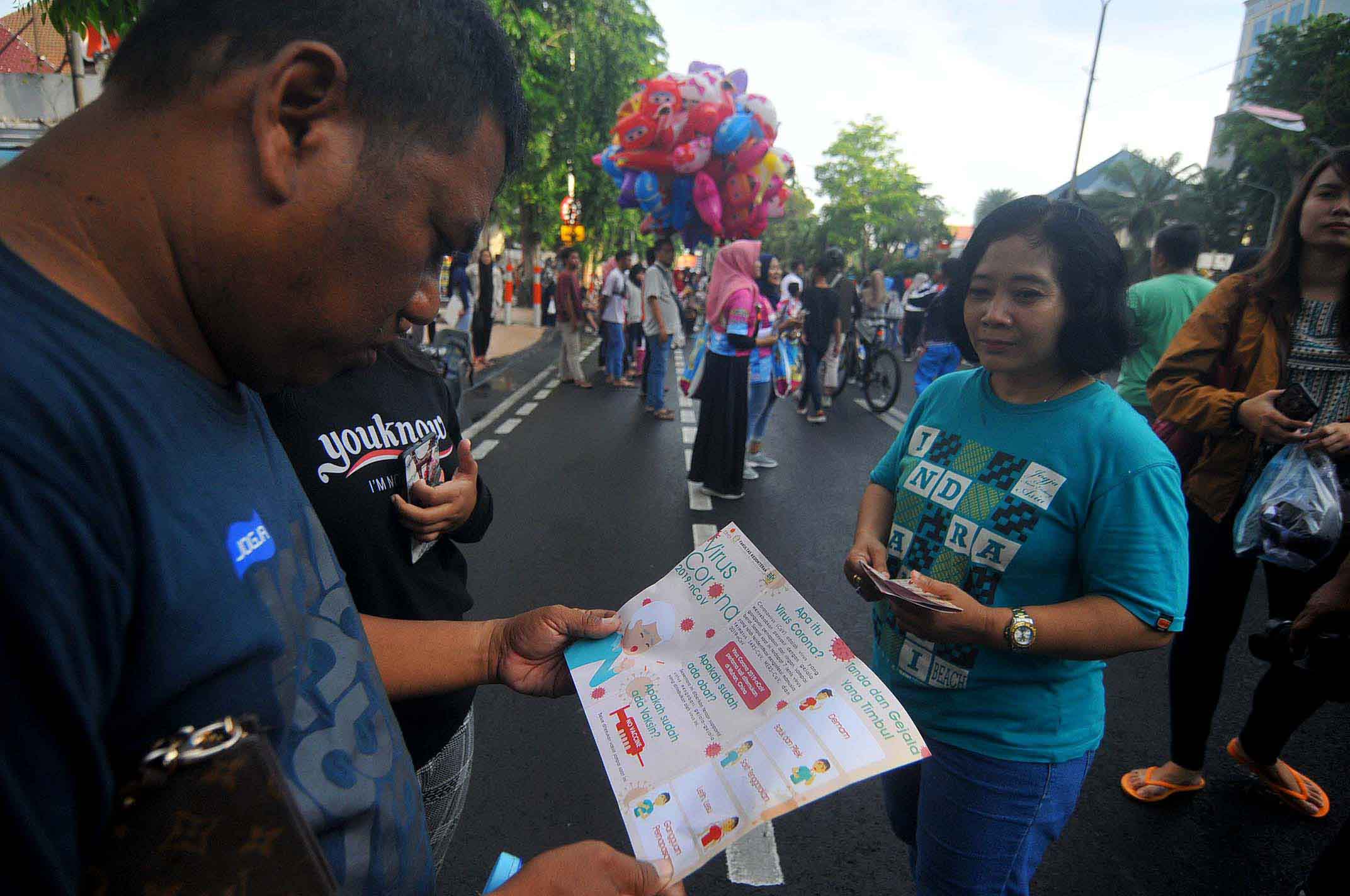 Warga membaca leaflet yang berisi informasi mengenai virus corona. (Foto: Erfan Hazransyah/nopibareng.id)
